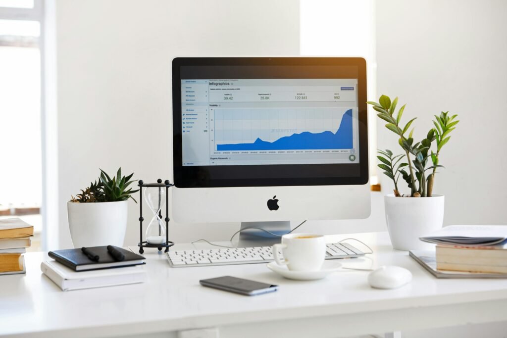 pexels-photo-572056-572056 A clean, contemporary workspace featuring a desktop with analytics on the screen and plants for a fresh look.